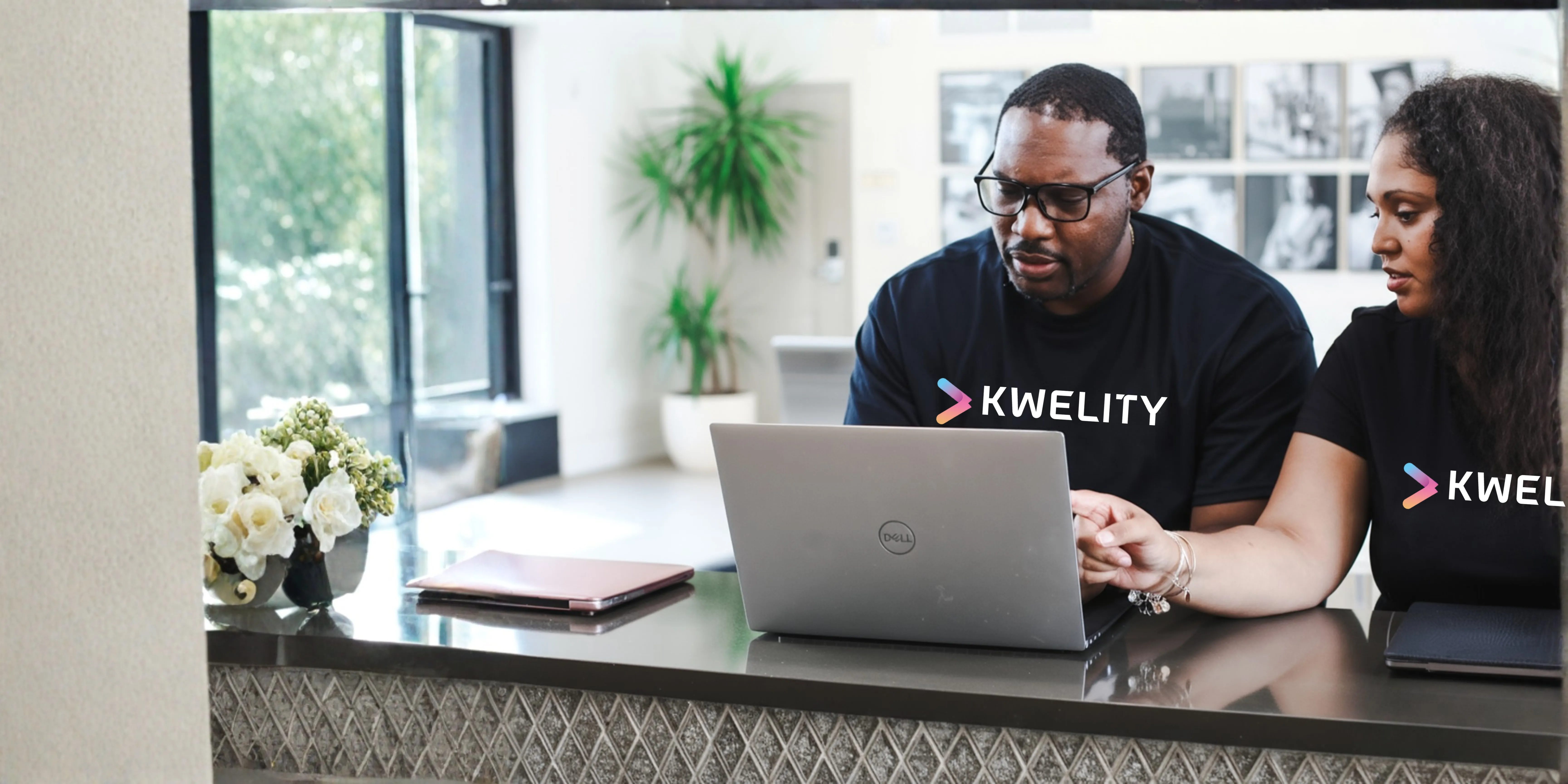 Two Kwelity team members working together at a laptop in the office